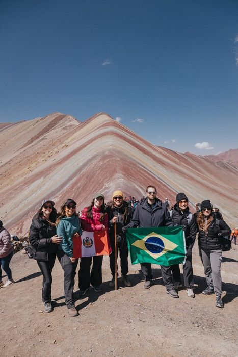 Grupo com as bandeiras do Peru e do Brasil diante de uma montanha colorida